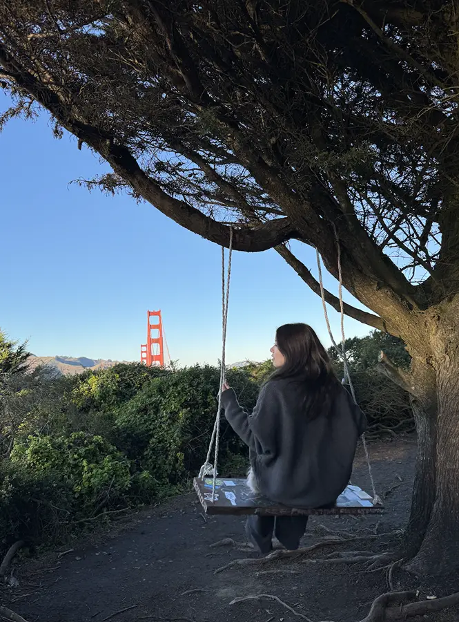 Wenjun on a tree swing overlooking the Golden Gate Bridge