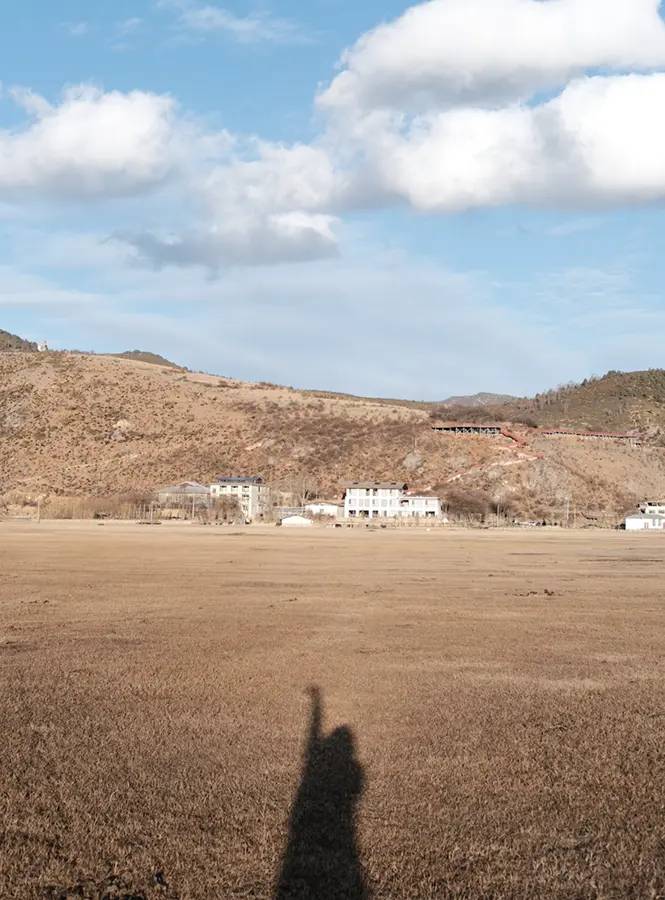 Wenjun's shadow stretching across a grassland beneath a blue sky